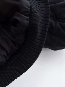 Detail view of black quilted winter jacket with ribbed elastic cuffs and diamond stitching