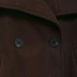 Detail of dark brown wool coat with notched lapel and black polished buttons
