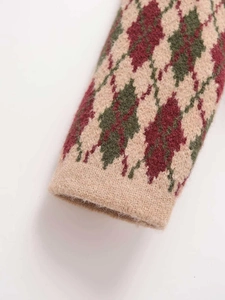 Close-up detail of argyle knit sweater cuff featuring red and green diamond pattern