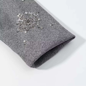 Detailansicht einer grauen Wolljacke mit feiner Perlenstickerei und silbernen Pailletten