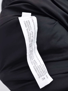 Detail view of the wash care label showing 100% cotton material on black winter coat