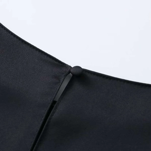 Detailed macro view of the black dress featuring a neat fabric-covered button and slit