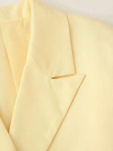 Gros plan du revers cranté classique sur un blazer jaune clair au tissu tissé texturé