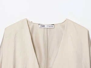 Macro shot of V-neck collar label and natural linen texture on a beige shirt