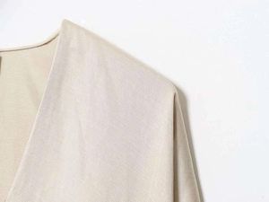 Detailed macro view of beige linen fabric texture and clean V-neck stitching on shirt