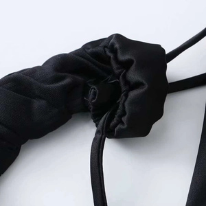 Macro detail of black summer dress featuring elegant ruched fabric and lace texture