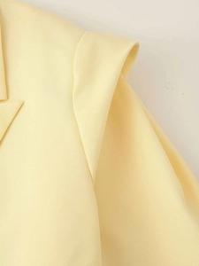 Détail macro du col d'un blazer jaune clair et texture du tissu tissé en gros plan