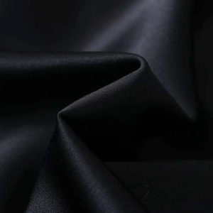 Detailed macro shot showing the smooth black satin fabric texture and elegant drape of dress