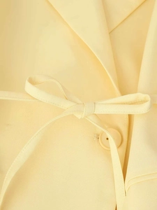 Détail d'un blazer jaune pâle avec une taille nouée et texture du bouton assortie