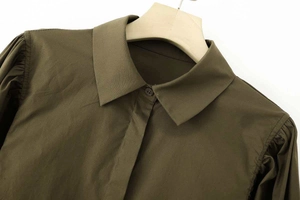 Détail d'une chemise en popeline vert armée avec col pointu et plis aux manches bouffantes