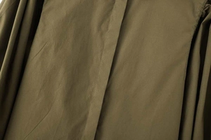 Détail d'une chemise en popeline vert olive montrant la patte cachée et les manches bouffantes