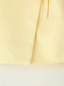 Détail du tissu tissé jaune clair montrant l'ourlet superposé et la texture sergée