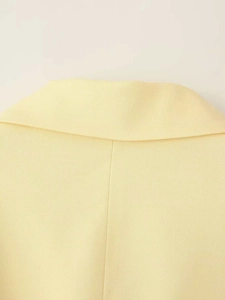 Gros plan détaillé du revers d'un blazer cintré jaune pâle pour femme au fini soigné