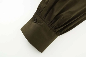 Détail d'une chemise en popeline vert olive avec manche bouffante plissée et poignet boutonné