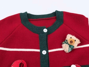 Detail of red Christmas knit cardigan with green trim and plush bear decoration