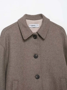 Detailed close-up of dark brown wool coat collar with classic lapel and black buttons