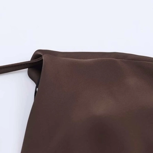Détail d'une robe en satin marron foncé avec coutures fines et bretelle mince