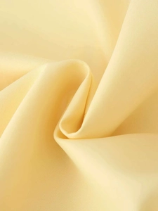 Détail du tissu du blazer jaune pâle montrant la texture lisse et l'éclat de la soie