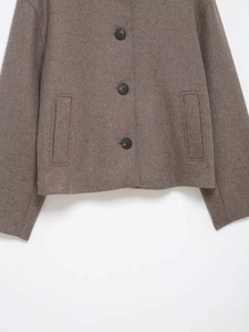 Close-up of brownish-grey wool jacket featuring three black buttons and vertical pockets