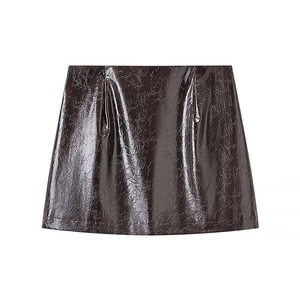 Detail of burgundy glossy faux leather mini skirt showing texture and reflective finish