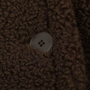 Detail of dark brown sherpa fleece fabric texture with a classic round four-hole button