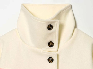 Detail shot of the cream wool coat featuring three elegant tortoise shell buttons and high neck