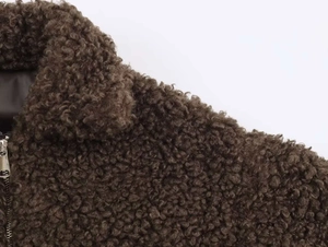 Detailed close-up of dark brown fleece jacket showing plush texture and metal zipper