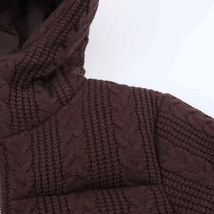 Detail view of dark brown cable-knit hooded jacket featuring thick textured fabric and lining