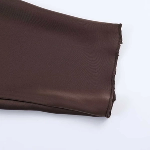 Détail de la texture du tissu en satin marron foncé et des coutures surjetées