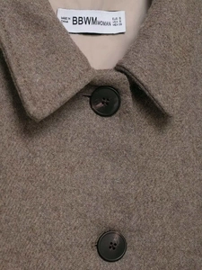 Detail view of brown wool jacket collar featuring classic lapel and black four-hole buttons