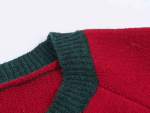 Detail of red knit sweater featuring a dark green ribbed neckline and soft wool texture