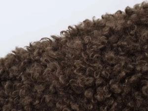 Macro texture of deep brown fleece fabric on long winter jacket showing thick curly fibers