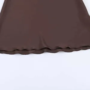 Détail de la robe en satin marron foncé montrant l'ourlet ondulé à bord laitue chic