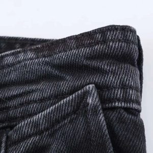 Détail du denim délavé gris foncé avec double couture robuste et texture de la matière