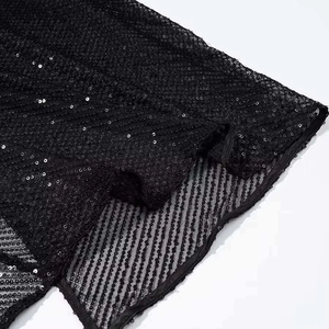 Detail of black sequin fabric with fine mesh base and side slit on a summer dress