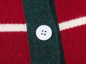 Detail of red and green knit sweater texture with white button and thick wool blend yarn