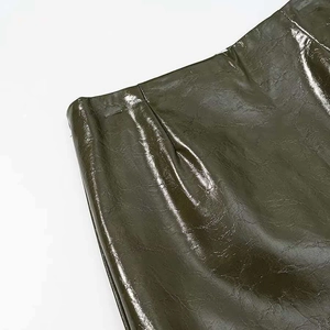 Detailed macro view of dark olive green patent leather texture with subtle glossy pleats