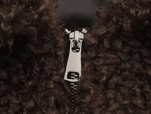 Detailed macro view of high-quality silver metal zipper on brown fleece winter jacket