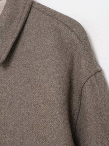 Close-up of shoulder stitching and wool blend texture on a dark brown cropped jacket