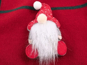 Close-up of a 3D Christmas gnome with white beard on red and green knit sweater