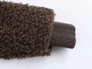 Detail of dark brown fleece jacket showing textured plush fabric and ribbed knit cuffs