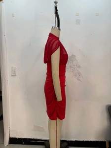 Detail of red ruched mini dress featuring mesh cape overlay and sleeveless design
