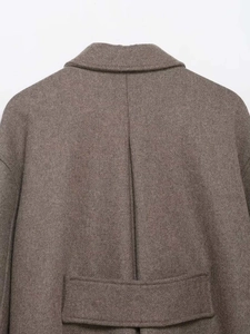 Detail view of the back seams and decorative waist strap on this brown wool blend coat