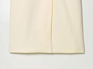 Detailed view of cream wool coat hem featuring neat stitching and textured fabric