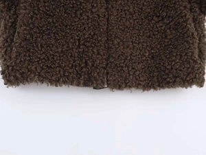 Close-up detail of dark brown fleece texture and metal zipper on long jacket hem