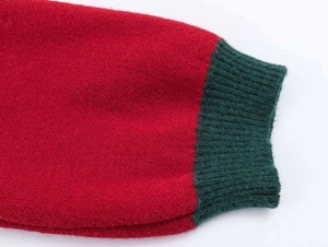 Close-up of red knit sweater sleeve with green ribbed cuffs and thick woolen texture
