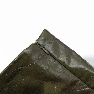 Detailed macro view of an olive green faux leather garment with a seamless hidden zipper