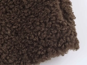 Close-up of deep brown teddy fleece fabric texture with curly faux fur fibers