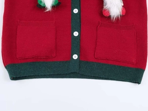 Detail of red Christmas knit cardigan with green trim and cute gnome plush accents