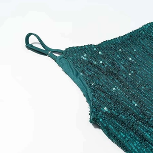 Detail of emerald green sequin dress with adjustable straps and luxury texture